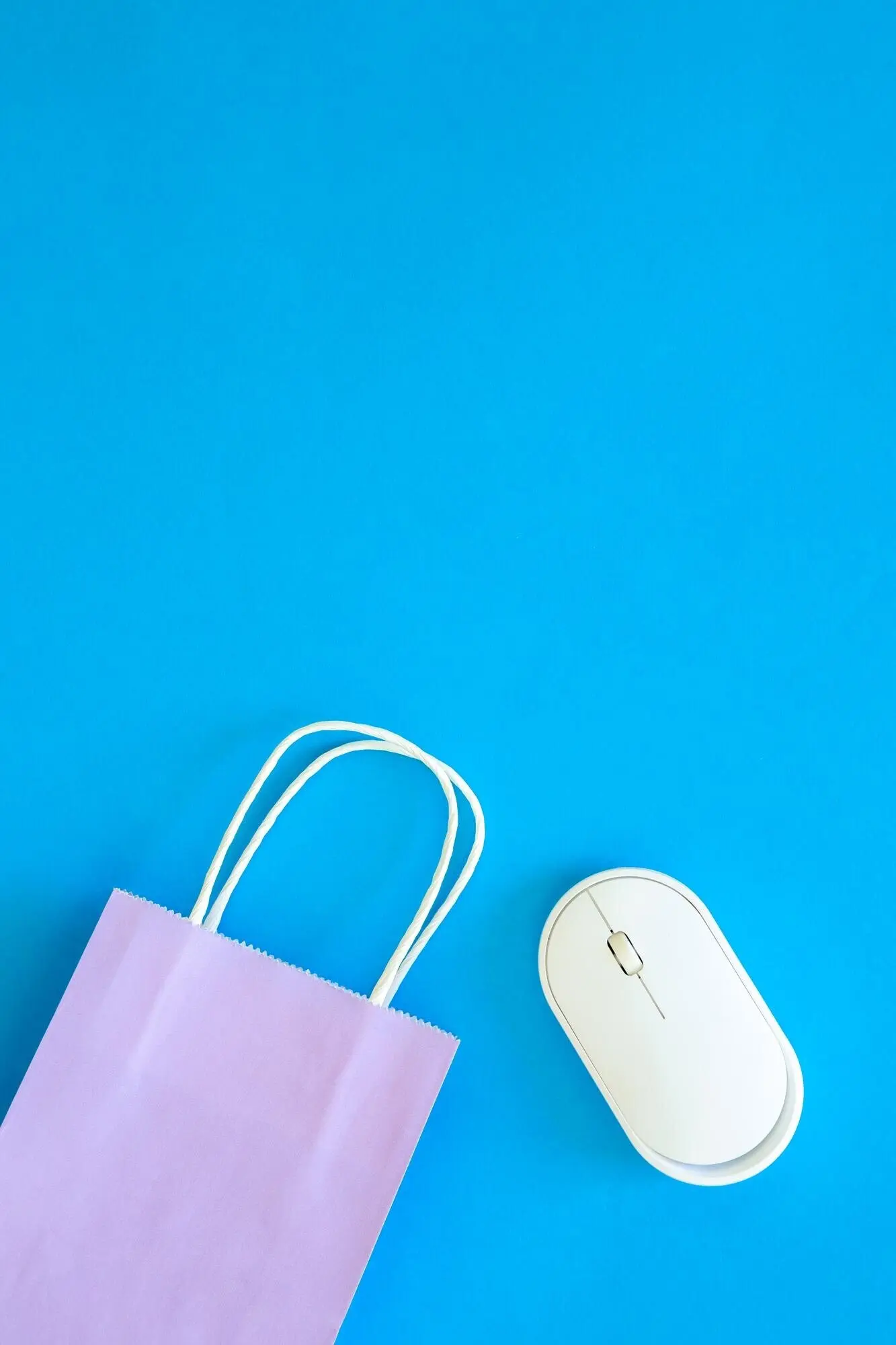 Computermaus und Papiertüte auf blauem Hintergrund, Ansicht von oben.